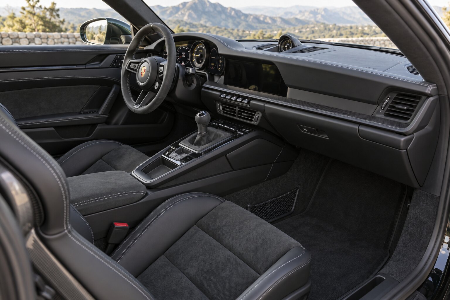 Illustrative view through the passenger doorway showing front seats, center console, steering wheel, and dashboard